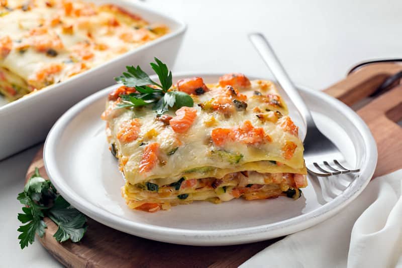Trozo de lasaña de verduras con capas imbricadas de pasta, zanahorias, calabacín y queso fundido.
